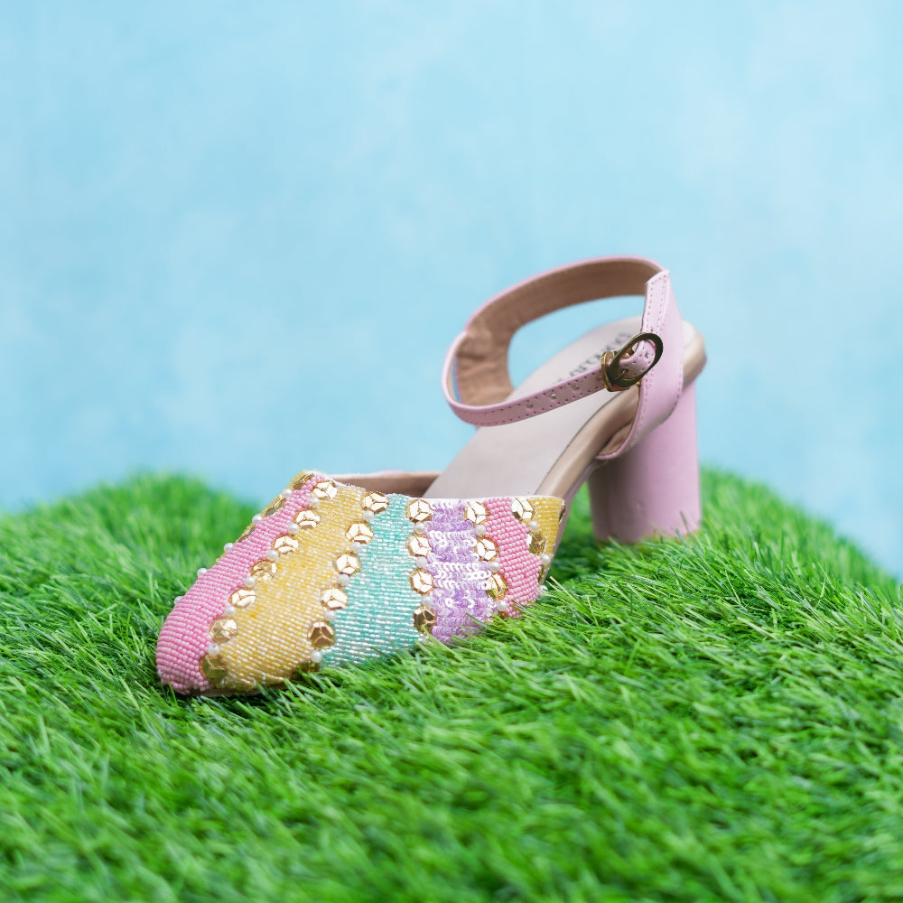 Colorful beaded sandal on a grassy surface with a blue background