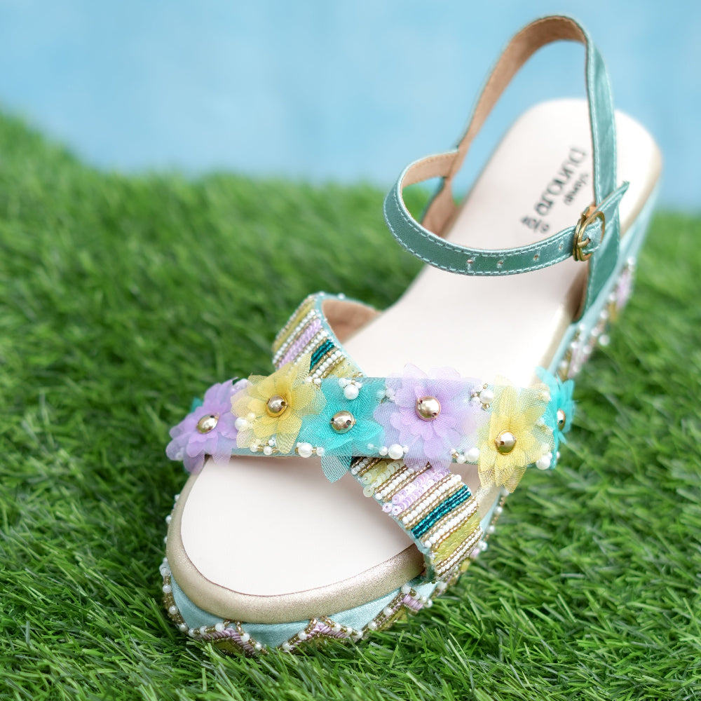 Decorative sandal with flowers and beads on a grassy background