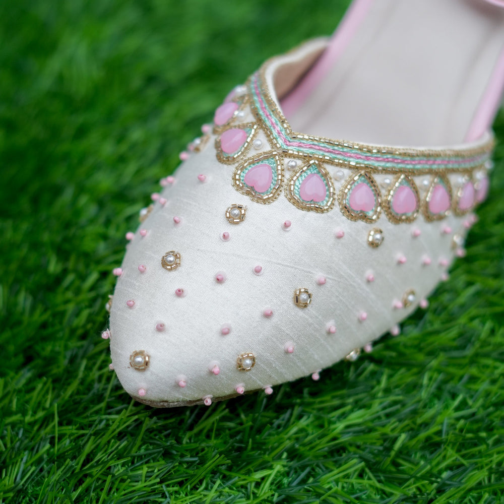 Decorative shoe with pink and gold embellishments on a green grass background