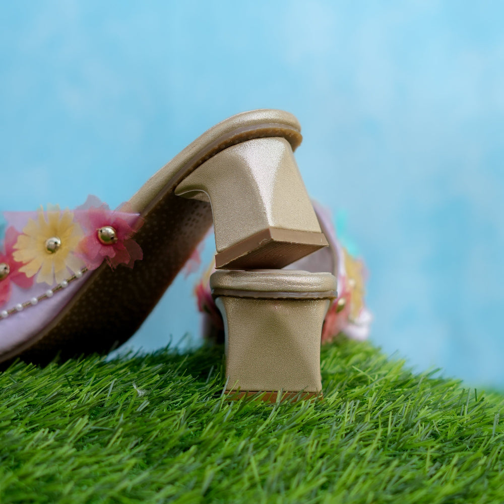 Beige sandal with floral design on grass against a blue sky