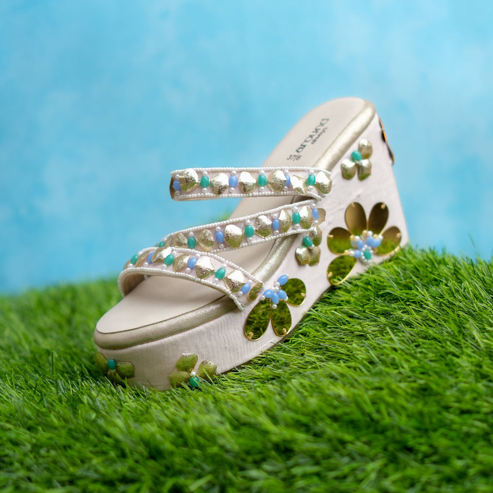 Decorative sandal with floral patterns on grass against a blue background