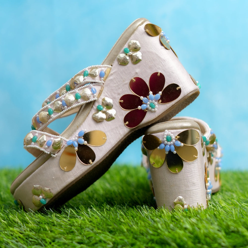Decorative shoes with floral designs on a grassy surface with a blue background