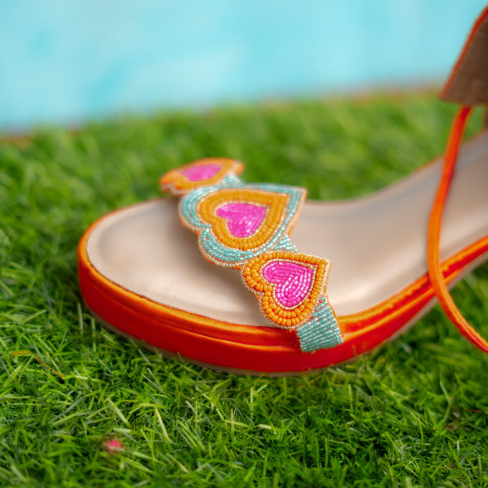 Decorative sandal with heart patterns on a grassy background