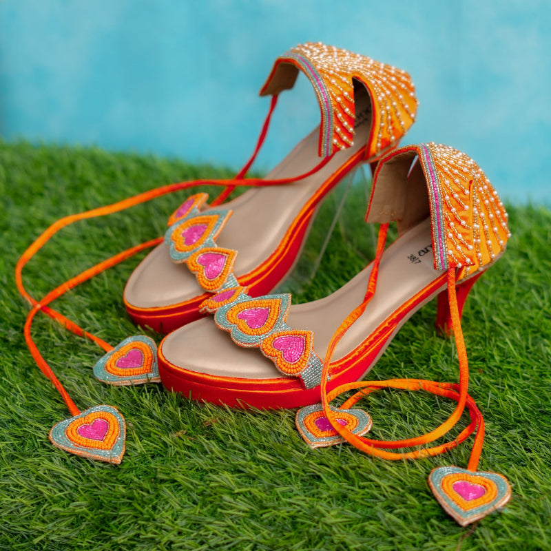 Colorful high-heeled shoes with heart designs on a grassy background