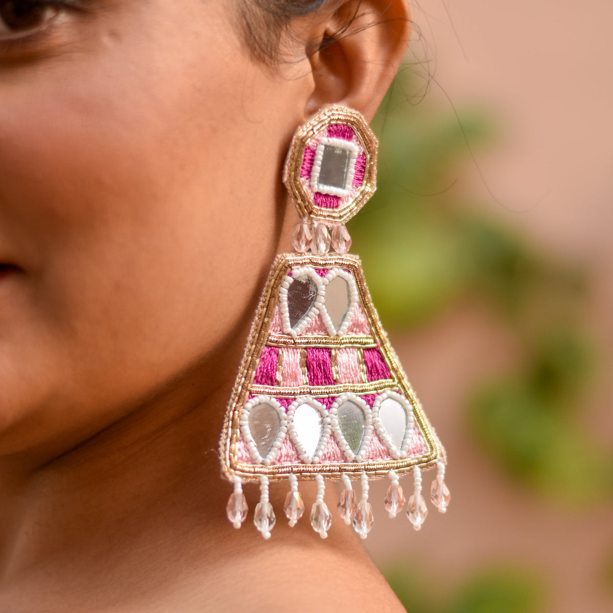 A bride to be wearing a decorative earring with intricate mirror work design