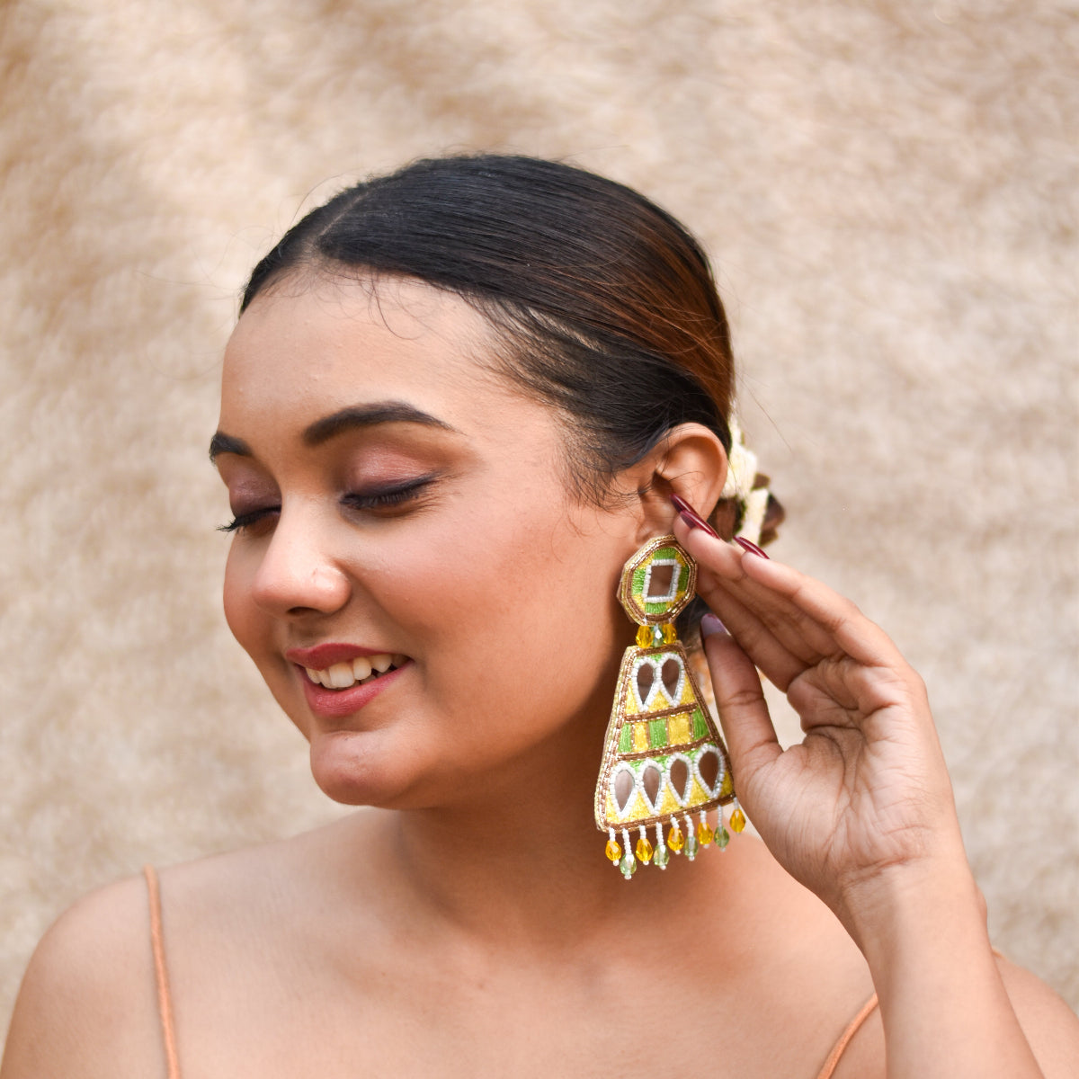 Woman wearing a large, ornate earring for a premium haldi look