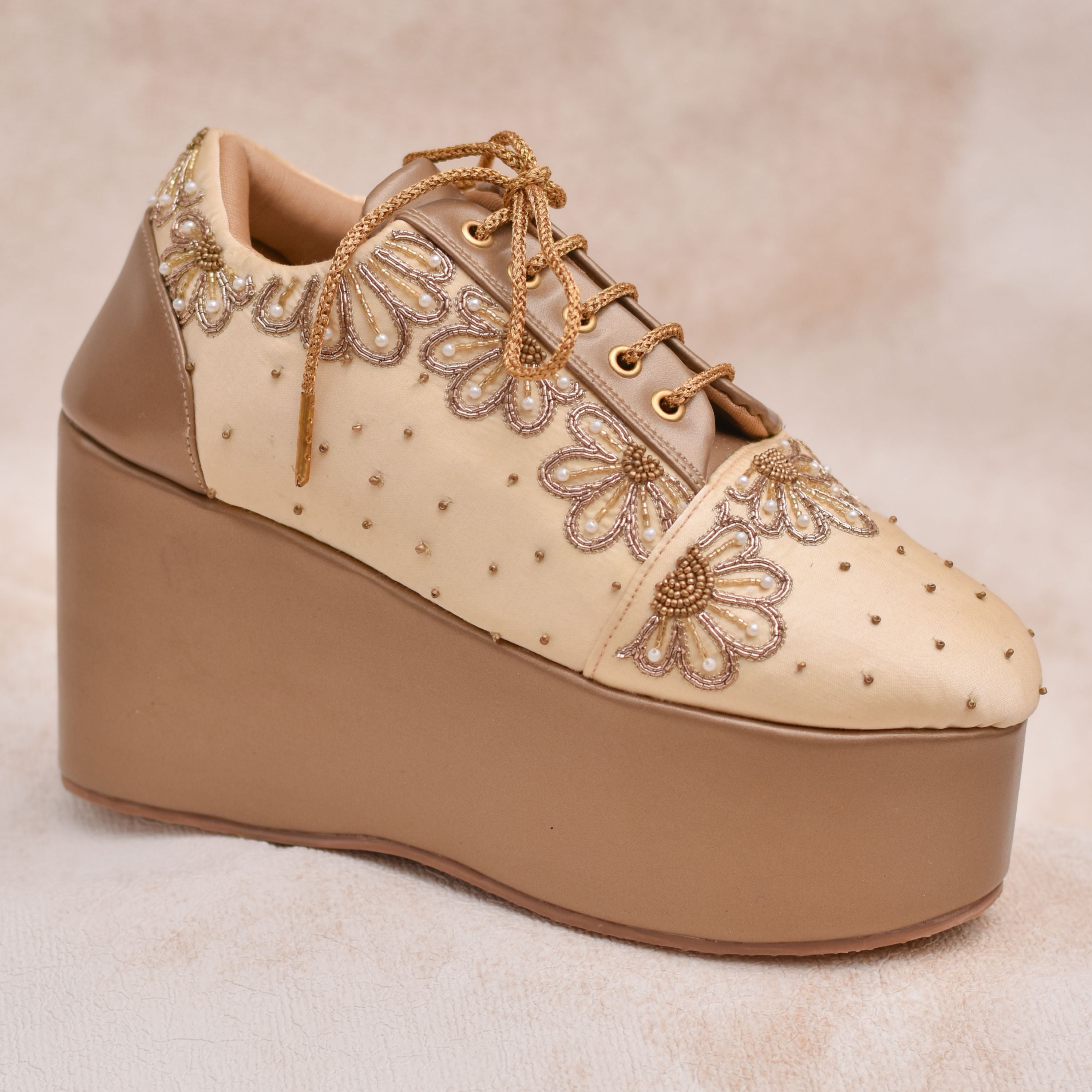 Designer champagne wedge sneaker with golden floral detailing and beadwork.