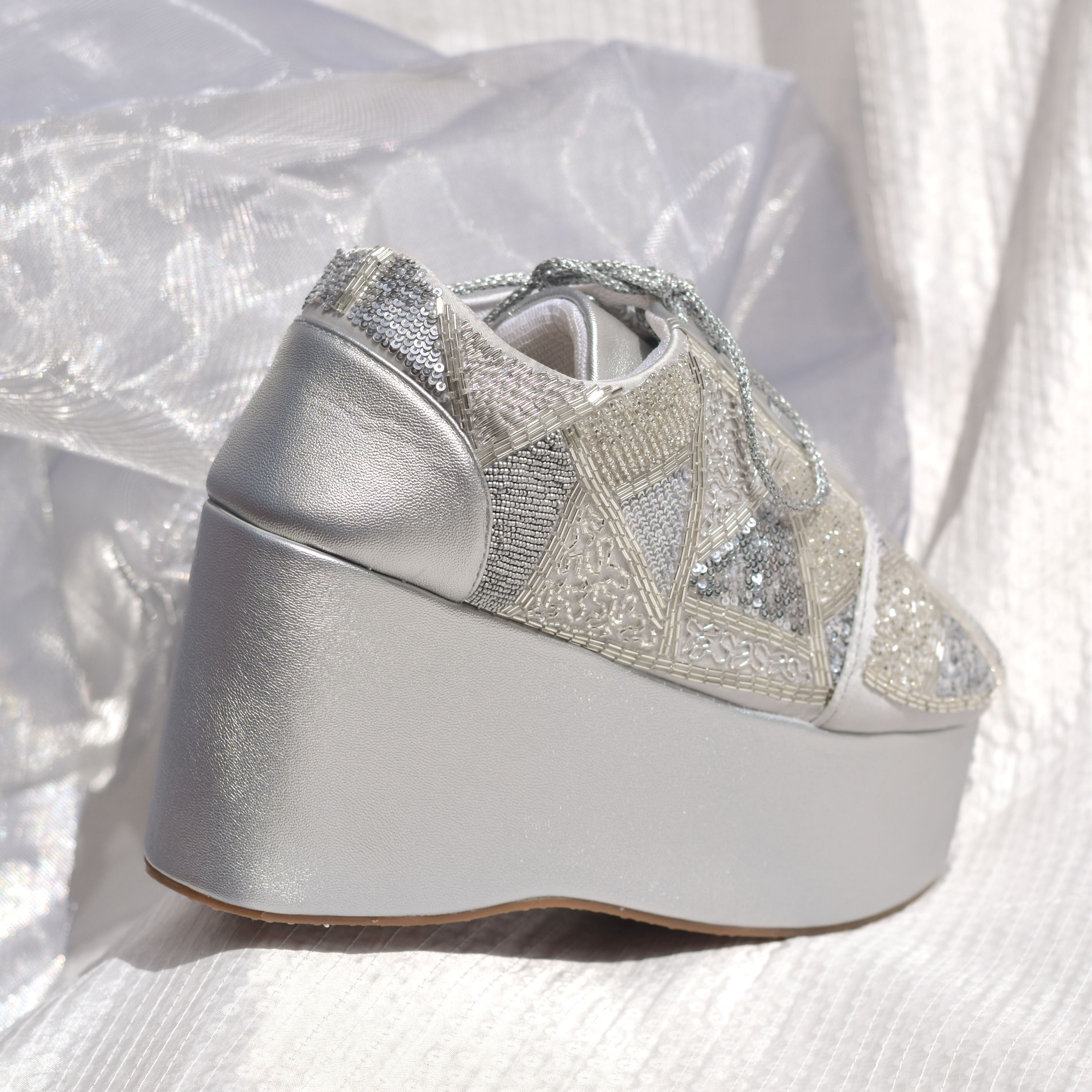 Designer silver sneakers with sequins, beads, and chunky wedge heel.