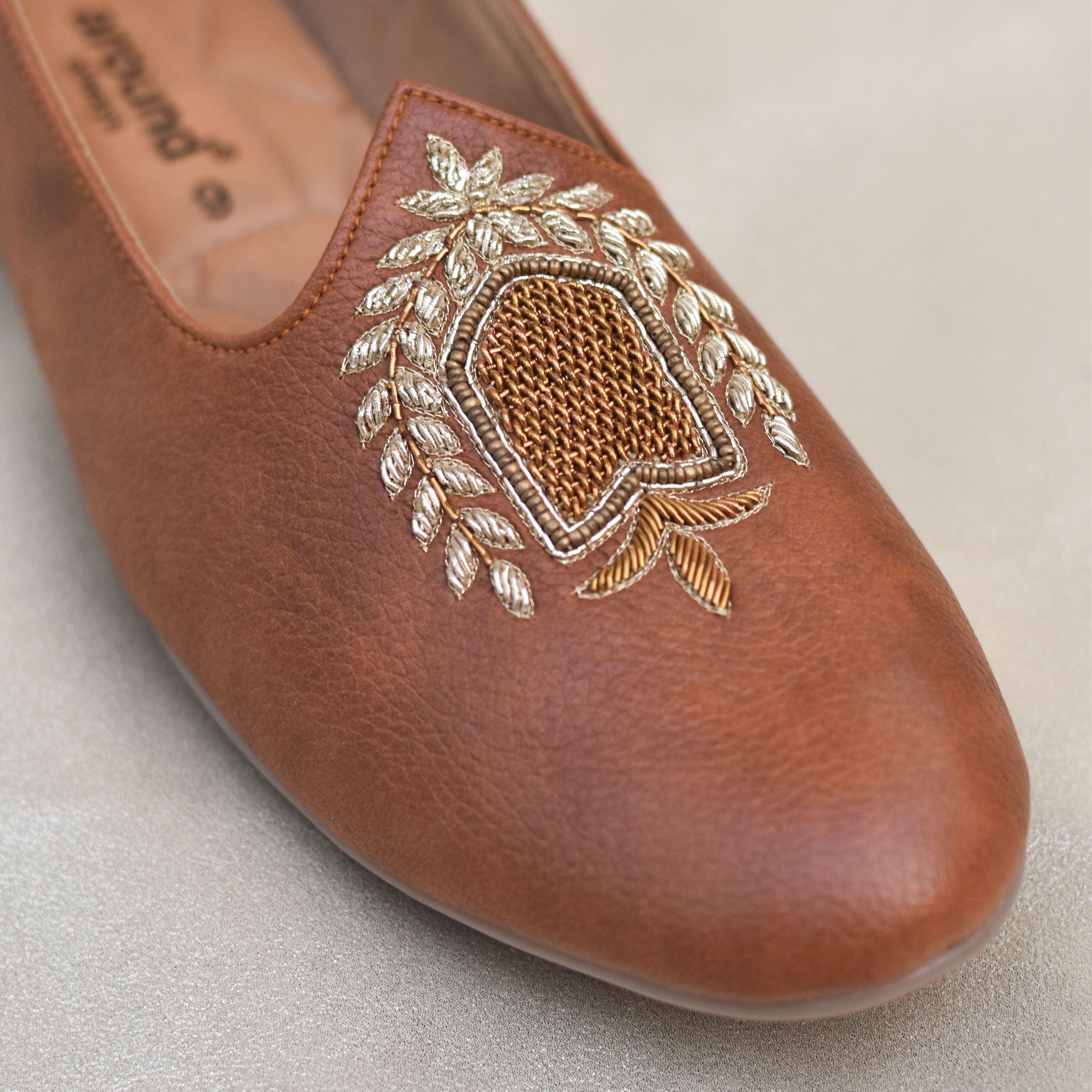 Groom's tan embroidered mojris with regal gold laurel crest and quilted insole and flexible insole.