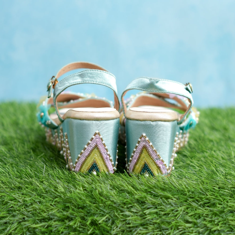  Turquoise blue high-heeled shoes with decorative patterns on a grassy surface
