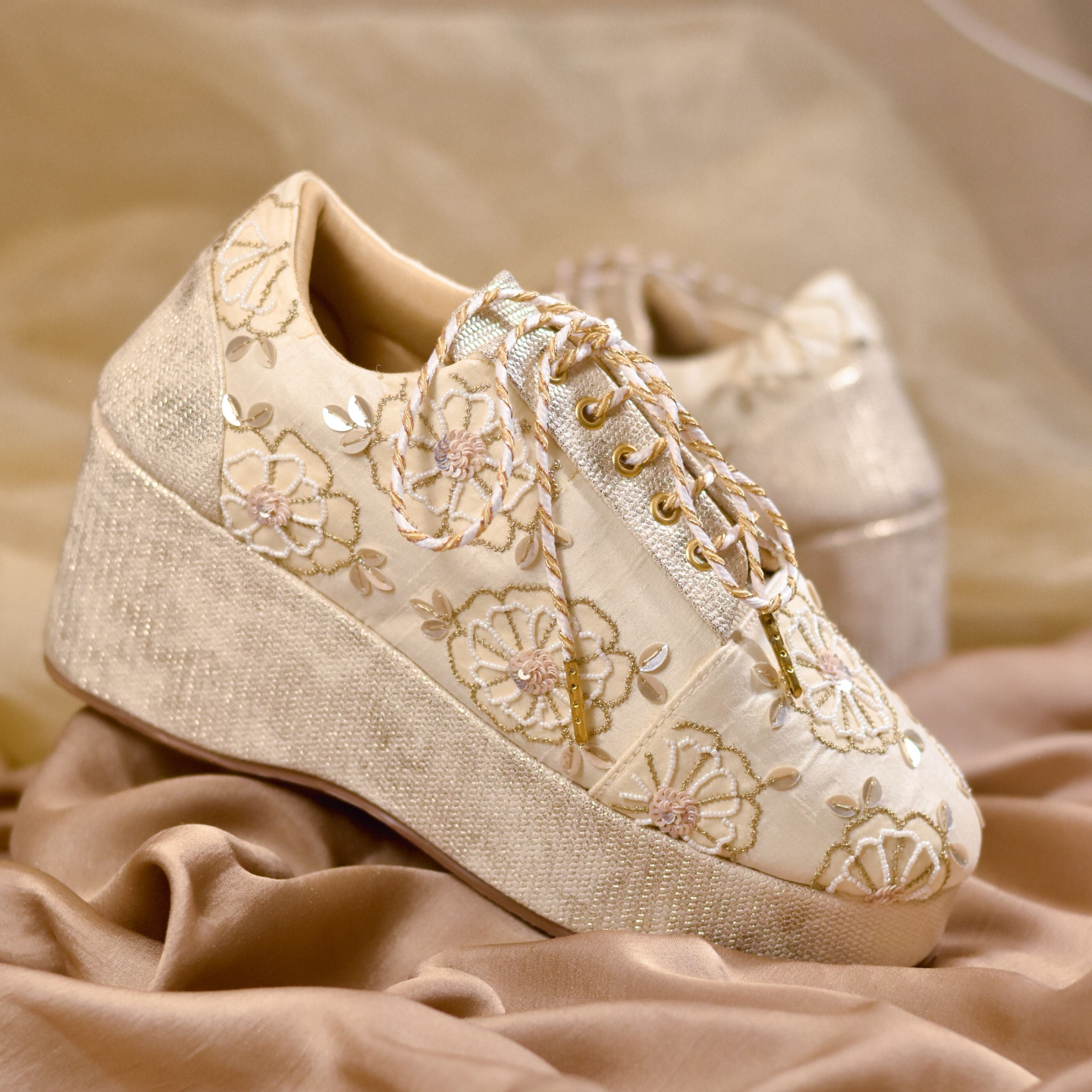 Ivory bridal sneakers with gold floral threadwork, sequins, and glitter laces.