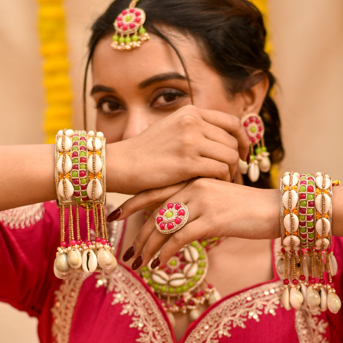 Bride wearing trendy haldi jewelry including bangles, earrings, and a ring made from multicolour beads