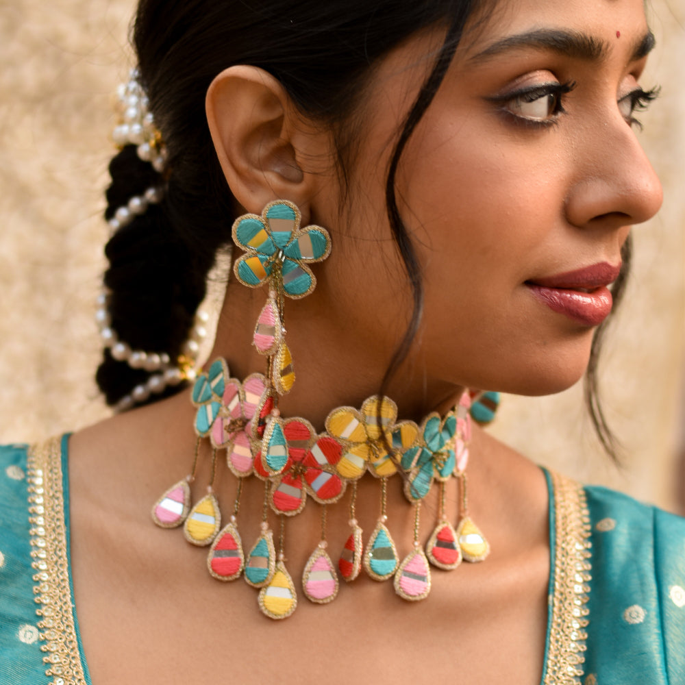 Bride wearing candy colors floral earrings and neckpiece made of mirrors for haldi