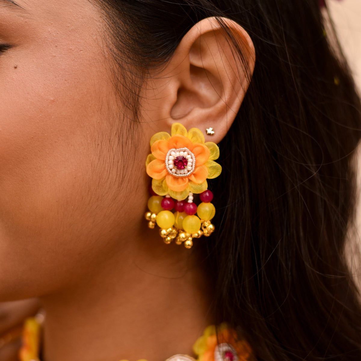 A bride wearing handmade floral earrings with bead drops for her haldi outfit 