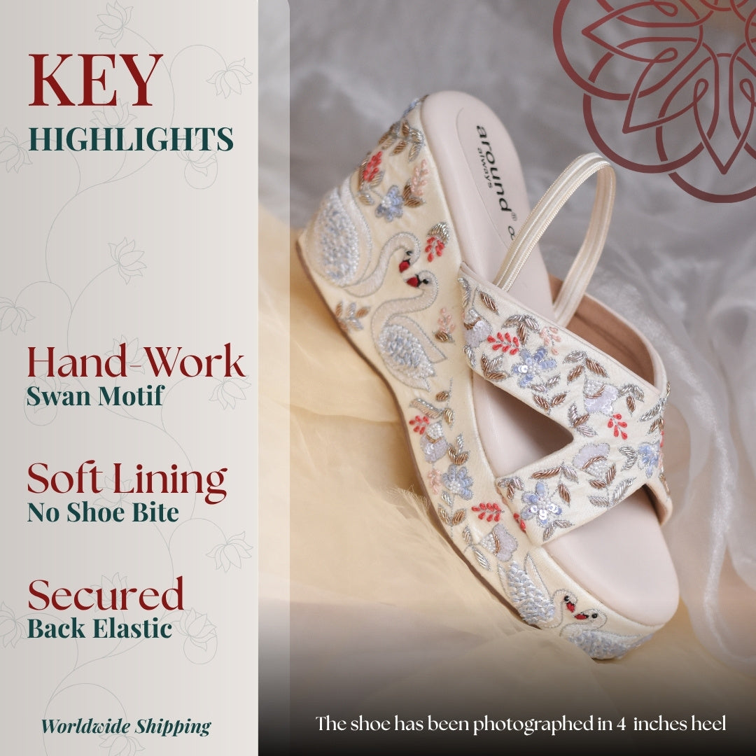 Ivory wedge sandals with hand embroidered swan motif, cross straps and elastic back support for secure fit