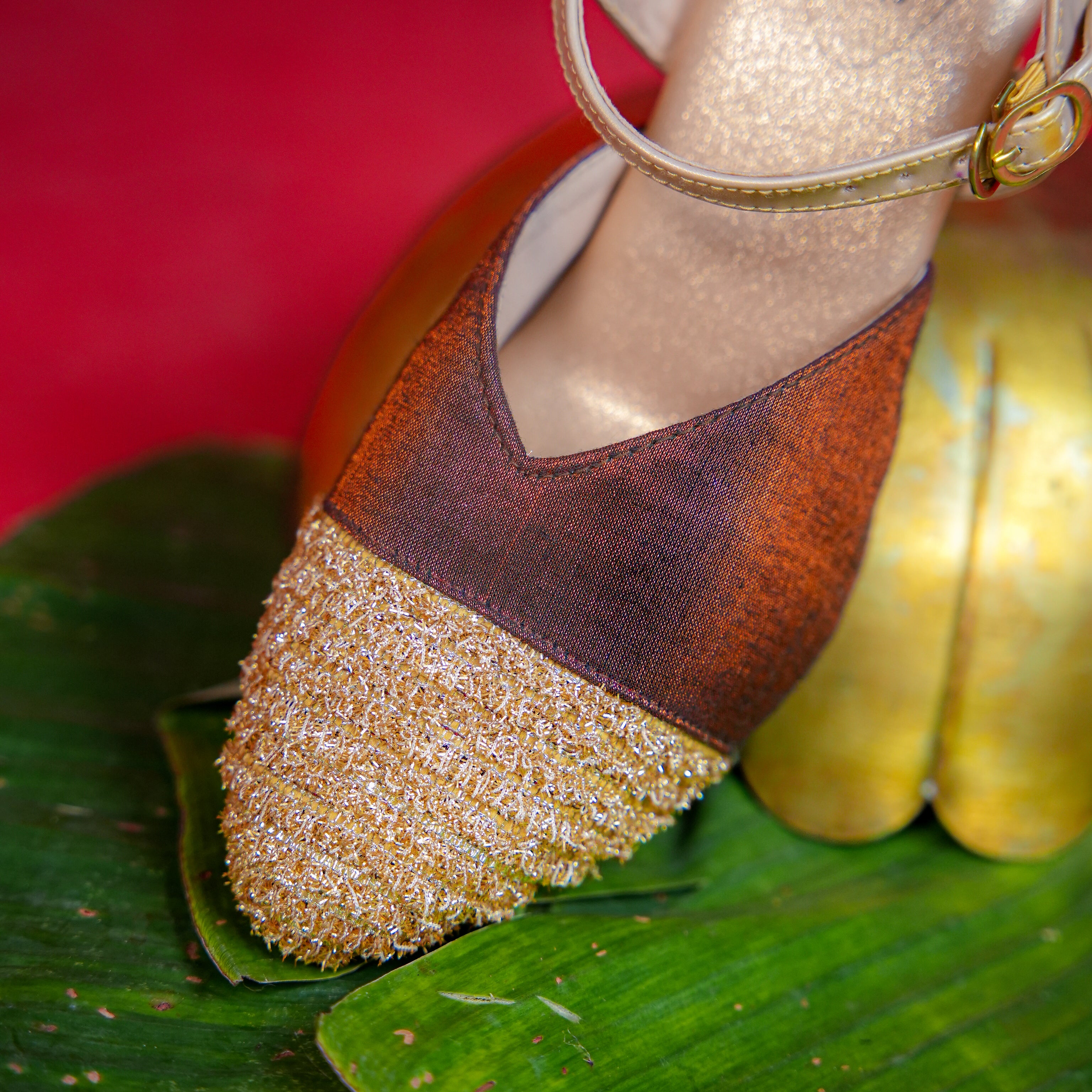 Close-up of brown and gold heeled footwear with textured front
