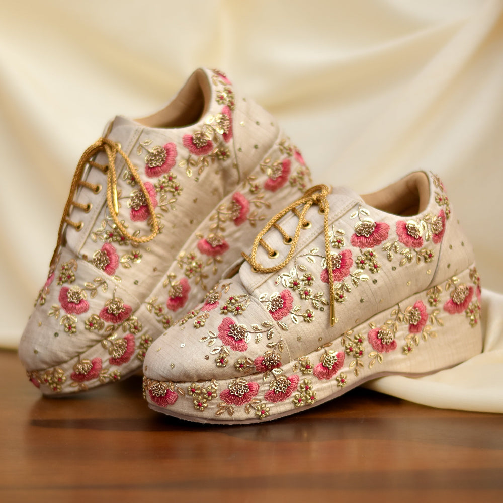 Embroidered beige sneakers with pink floral threadwork and gold lace detail