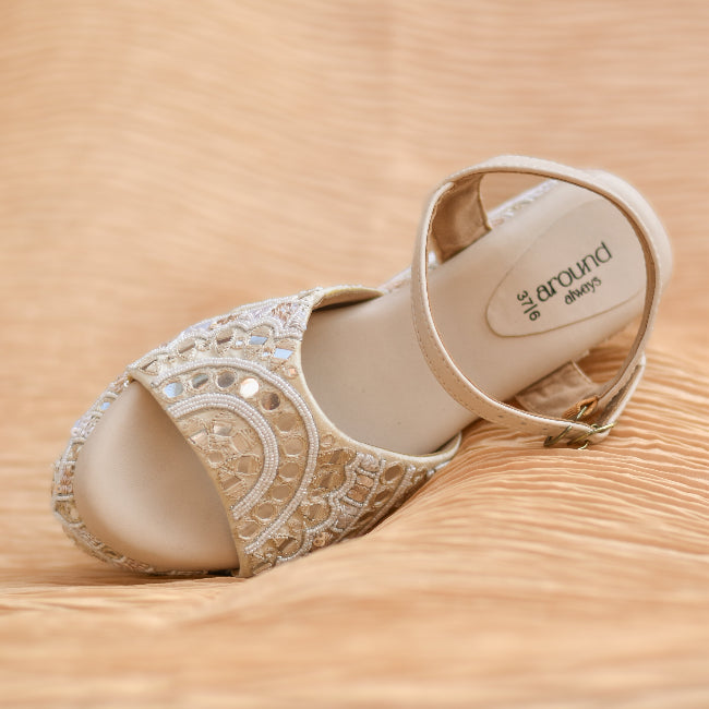 Close-up of ivory wedge heels with decorative mirror work all over