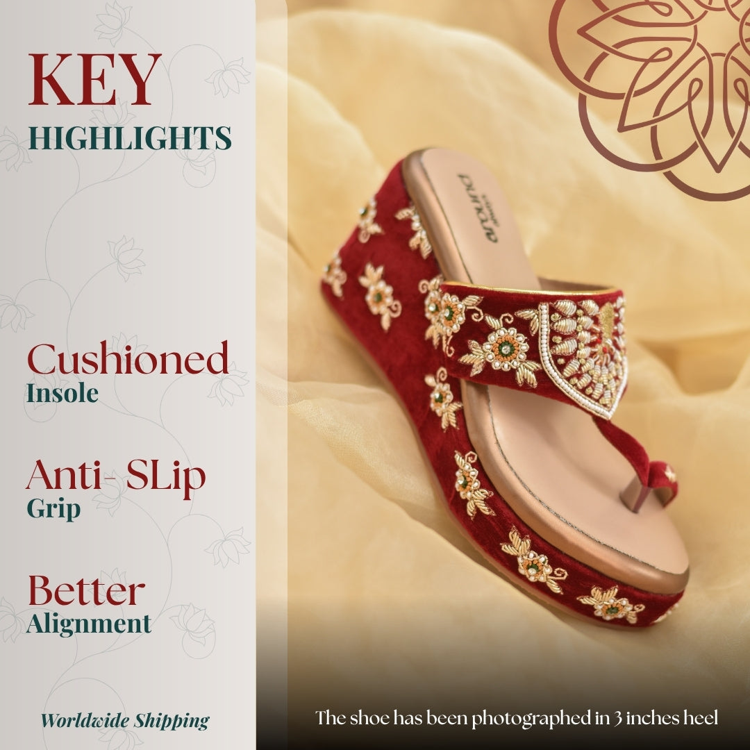 Red  wedge sandal with intricate floral handwork, styled on soft draped fabric backdrop for festive wear.