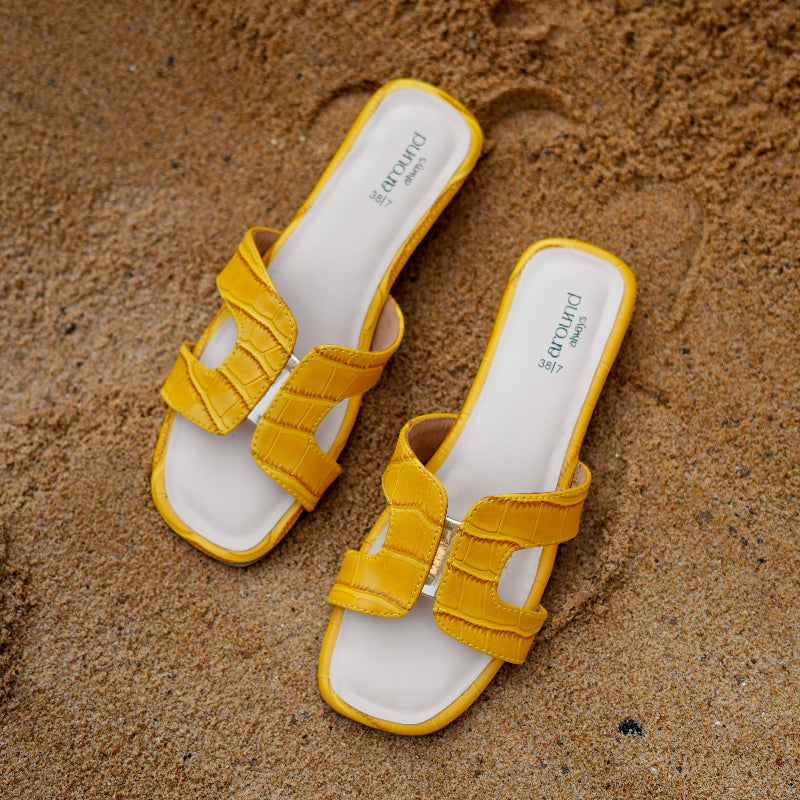 Mustard yellow flat slider with croc-textured straps and interlocked upper design