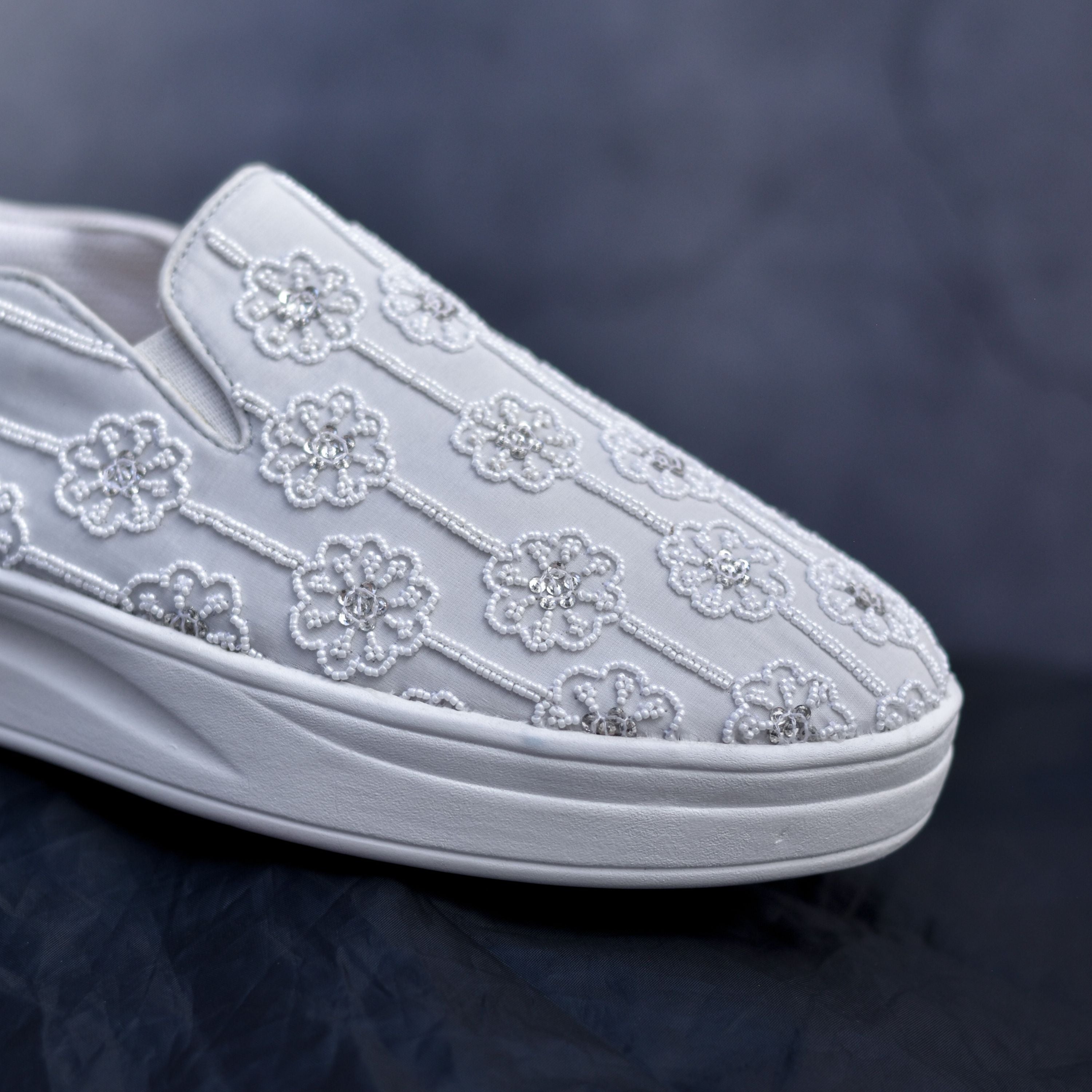 Women’s sneakers with white embroidered flowers and casual platform base.