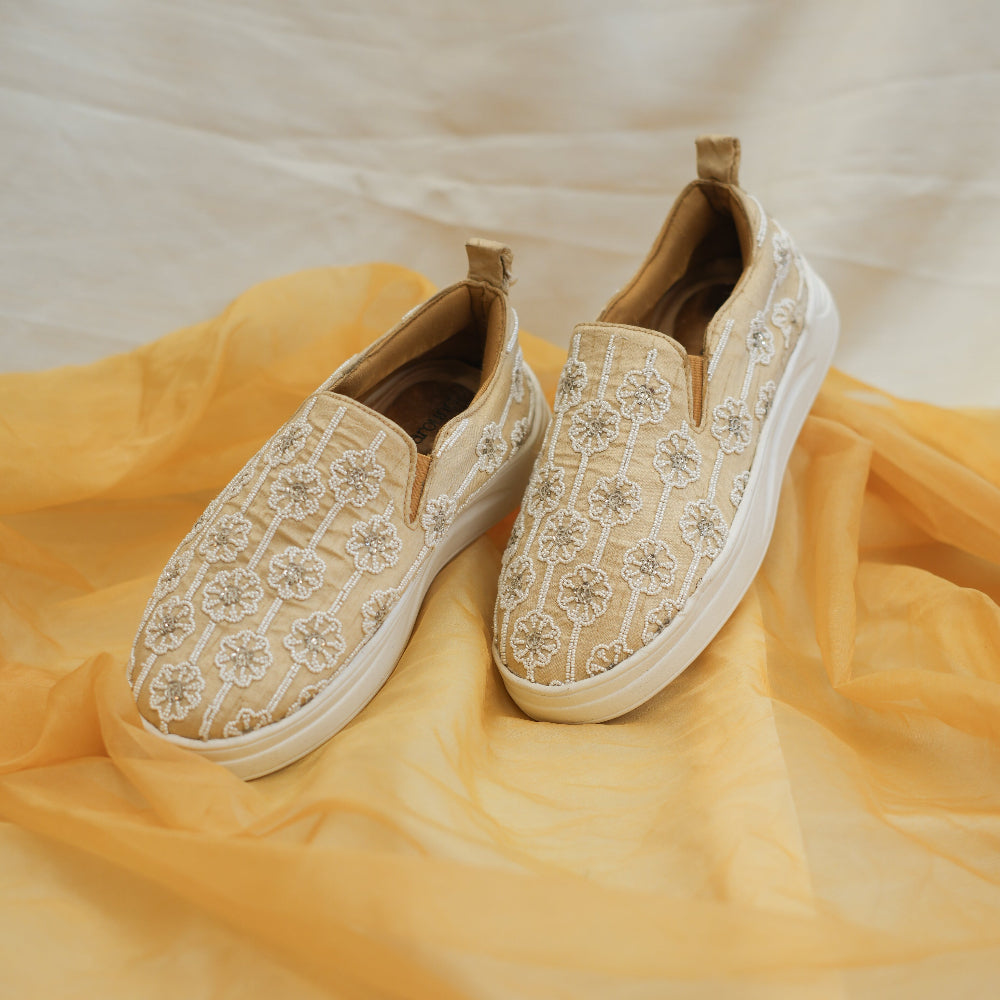 Beige bridal sneakers with repeating flower patterns and white platform sole
