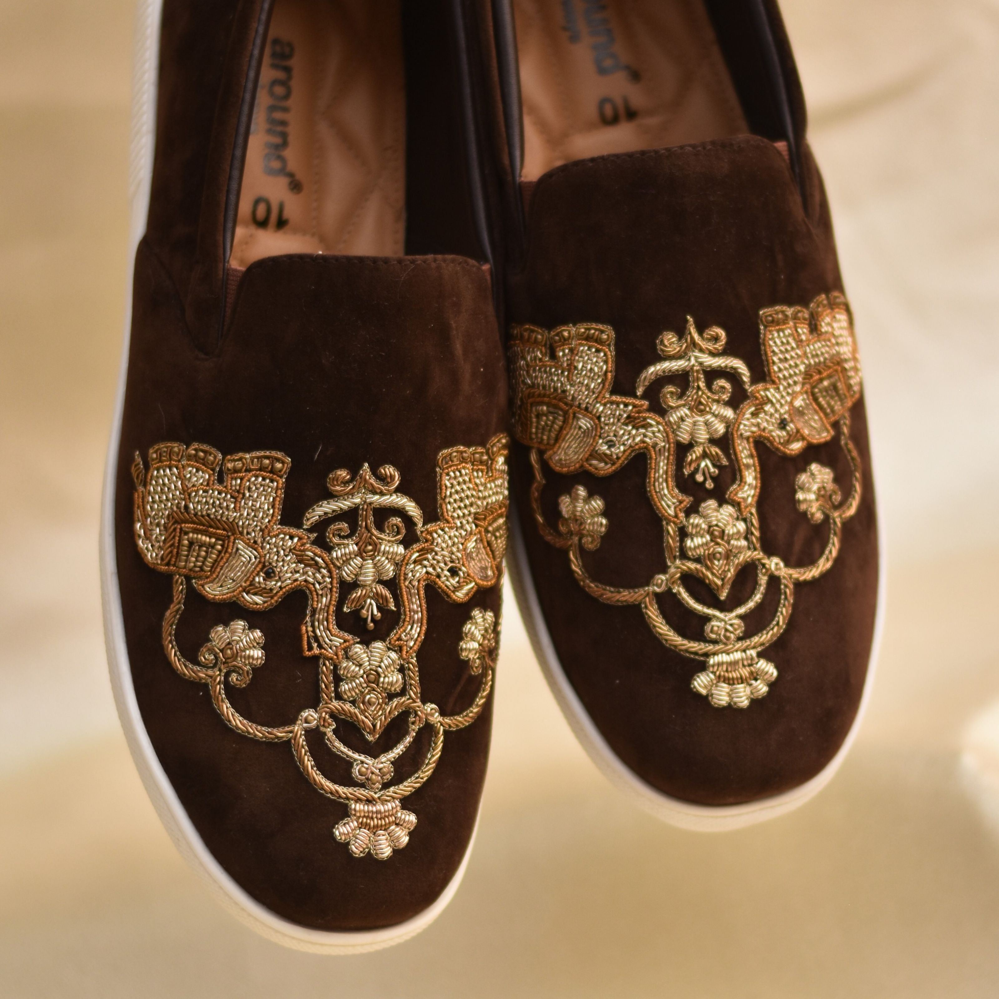 Detailed handcrafted wedding shoes featuring rich brown base and traditional motifs.