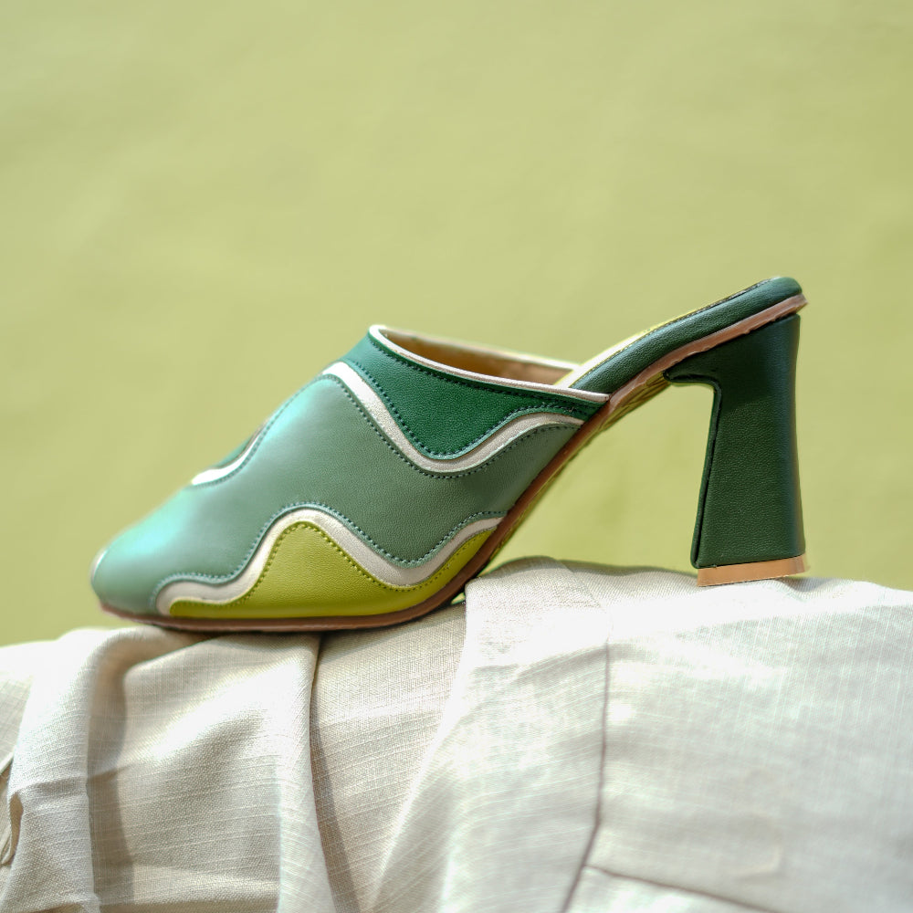 Contemporary green heeled mules with contrasting panels and pointed toe shape
