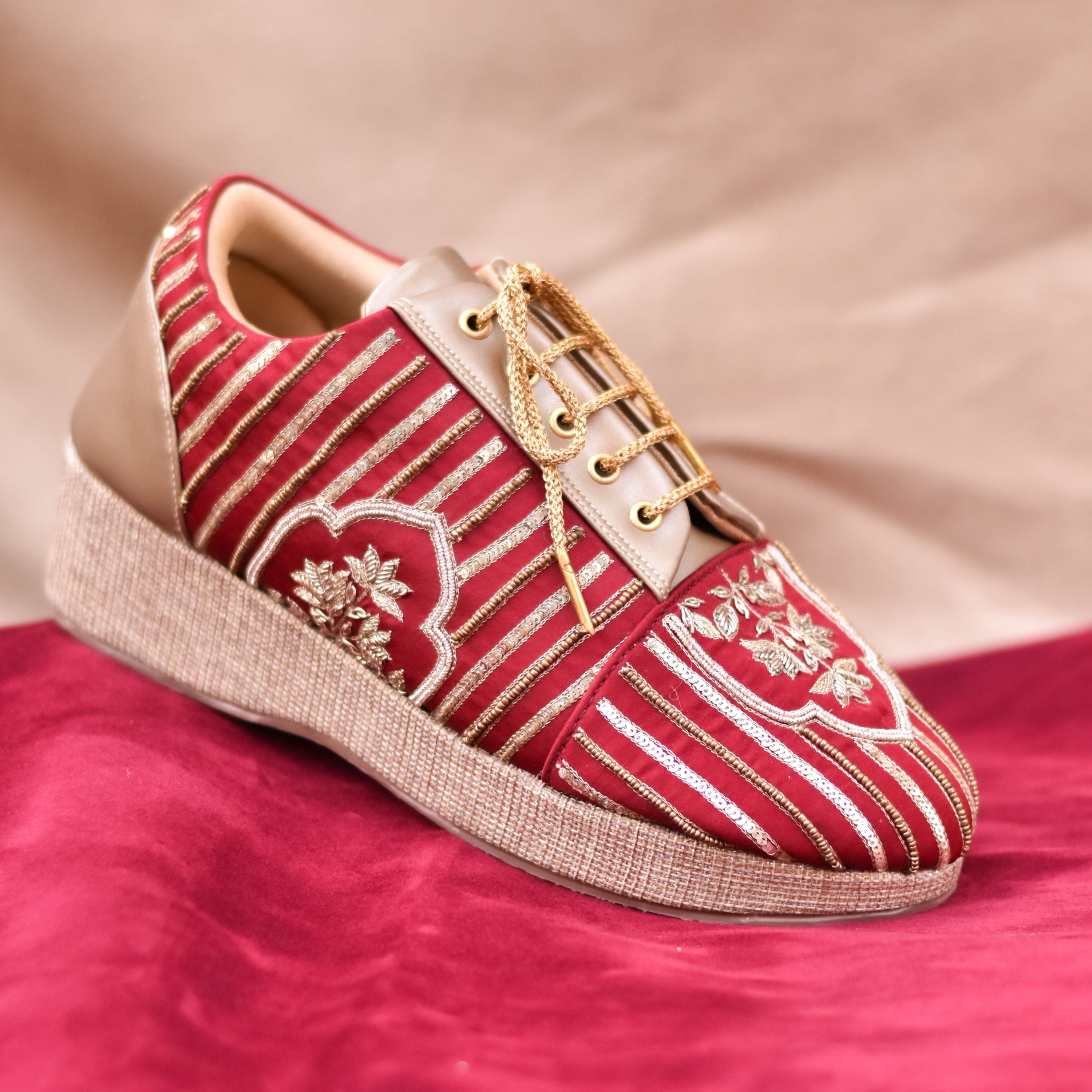 Festive women’s sneakers in red fabric with golden stripes and floral design.