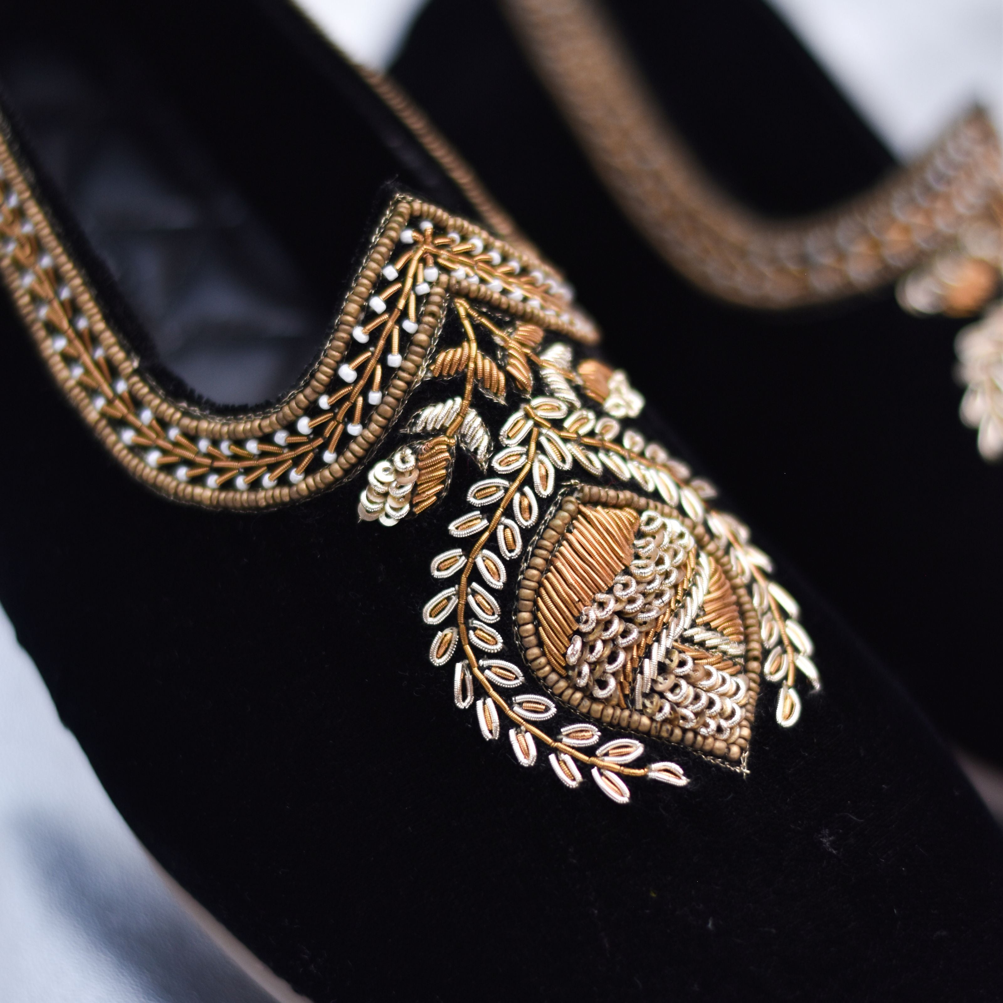 Elegant men's velvet footwear featuring intricate gold threadwork and textured borders.
