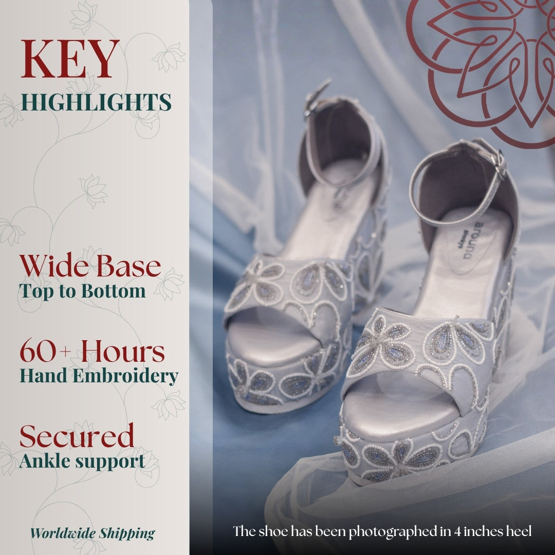 Silver high-heeled shoes with intricate floral designs and ankle strap for support 