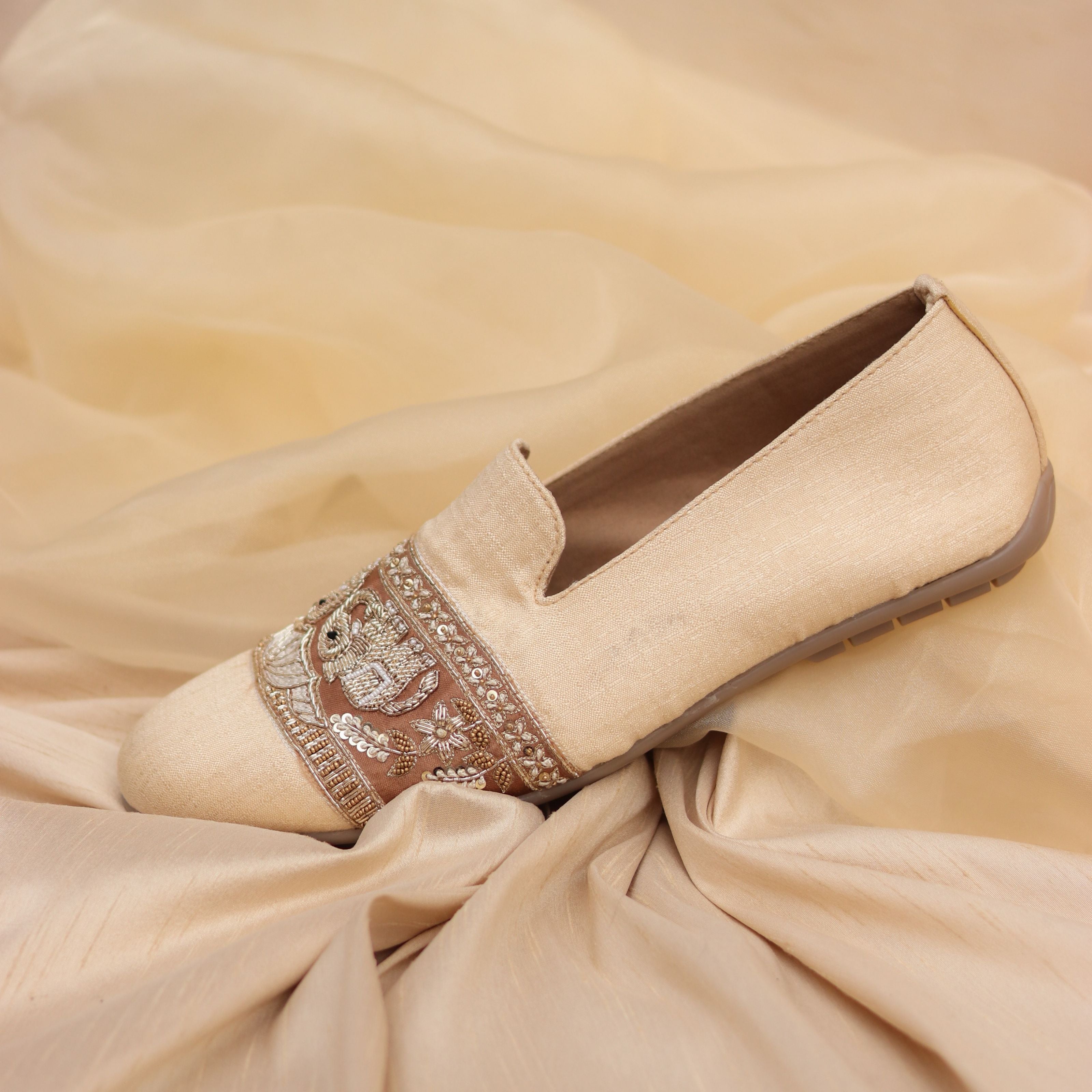 Beige fabric shoes with gold and bronze threadwork featuring elephant and leafy motifs.