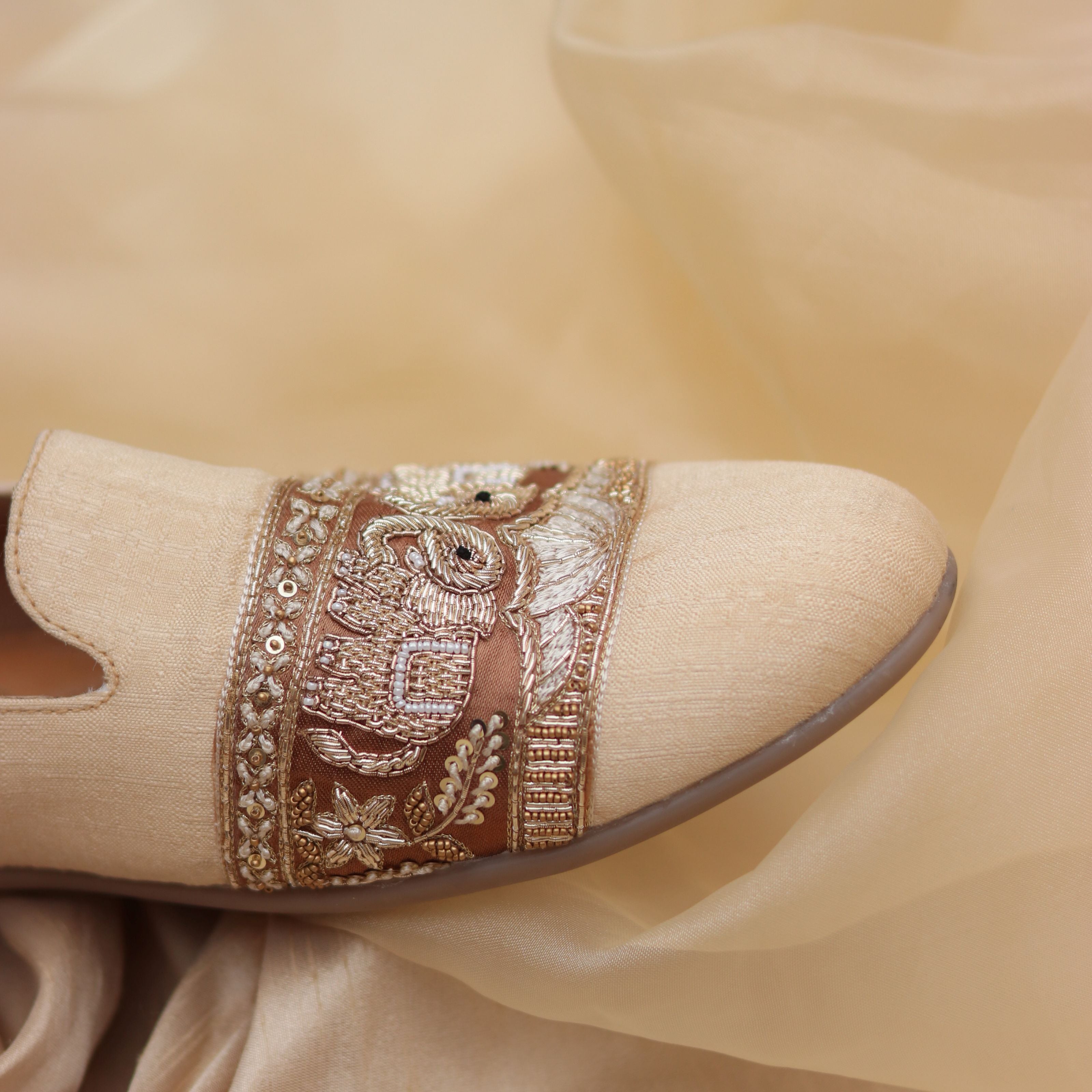 Elegant wedding footwear with intricate gold embroidery and soft sheen fabric.