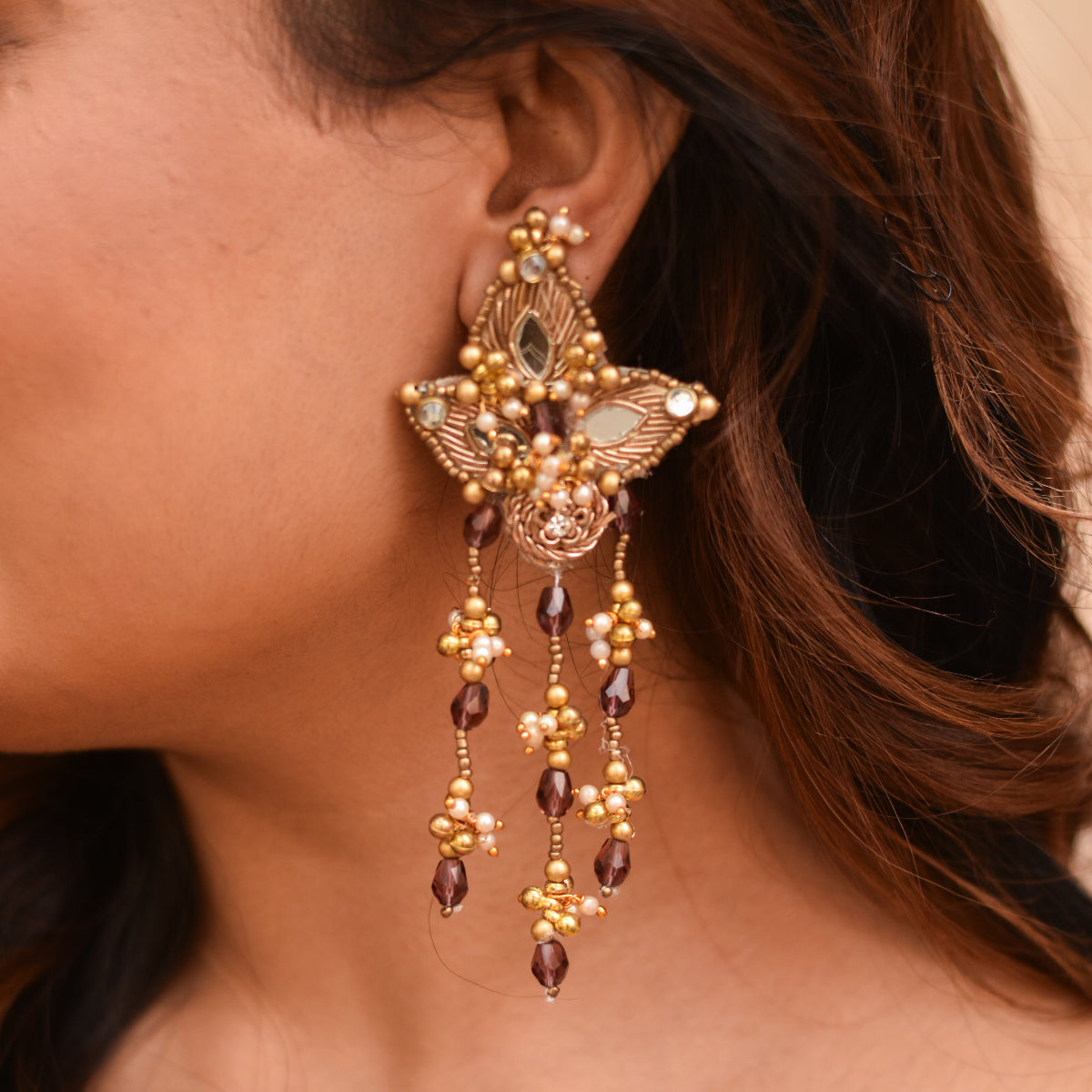 Antique-gold statement earrings with layered bead drops.
