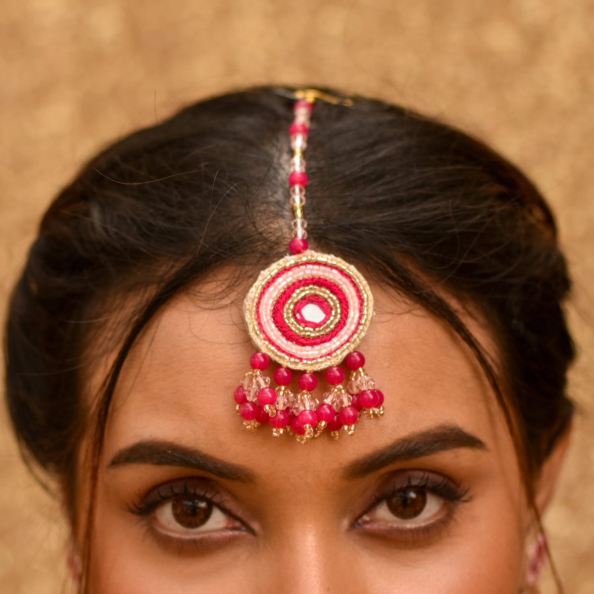 Indian bride wearing a pink beaded maangtika for her haldi ceremony