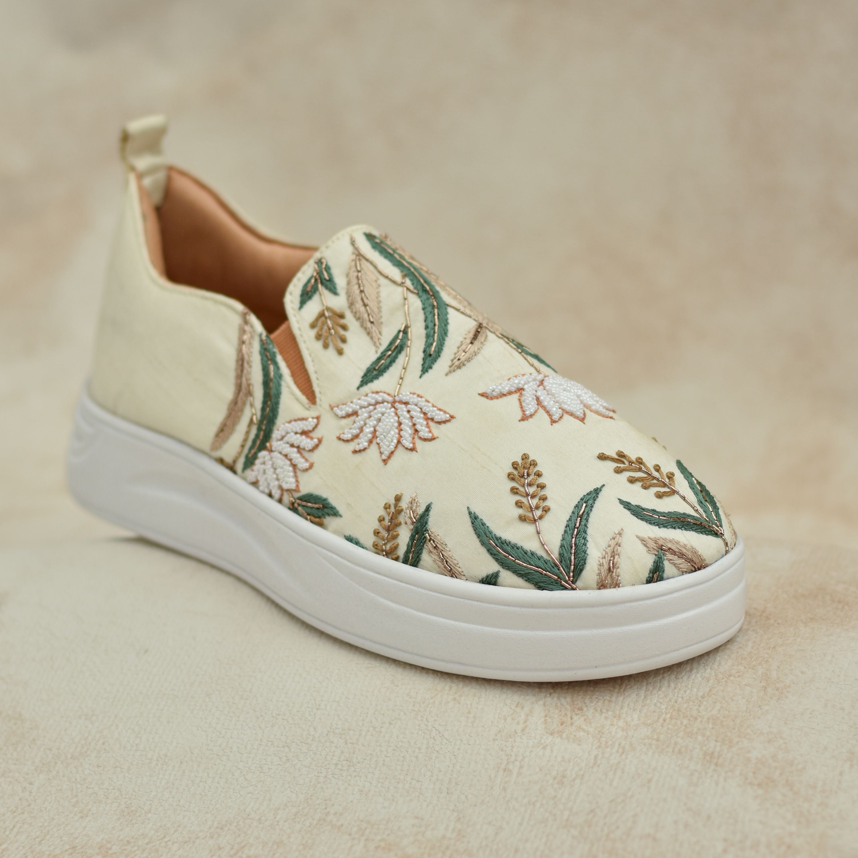 Festive slip-ons featuring embroidered flowers and leaves on beige fabric.