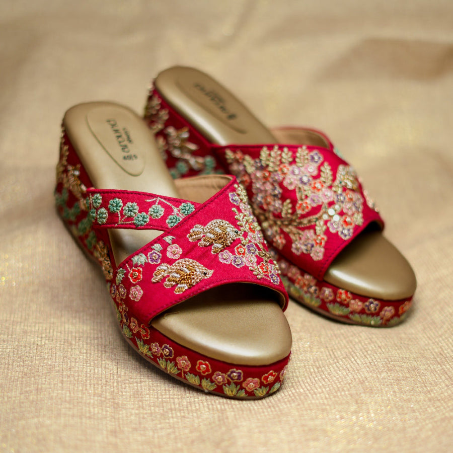 Reddish maroon wedge sandals with floral threadwork, bird motifs, and crossover straps
