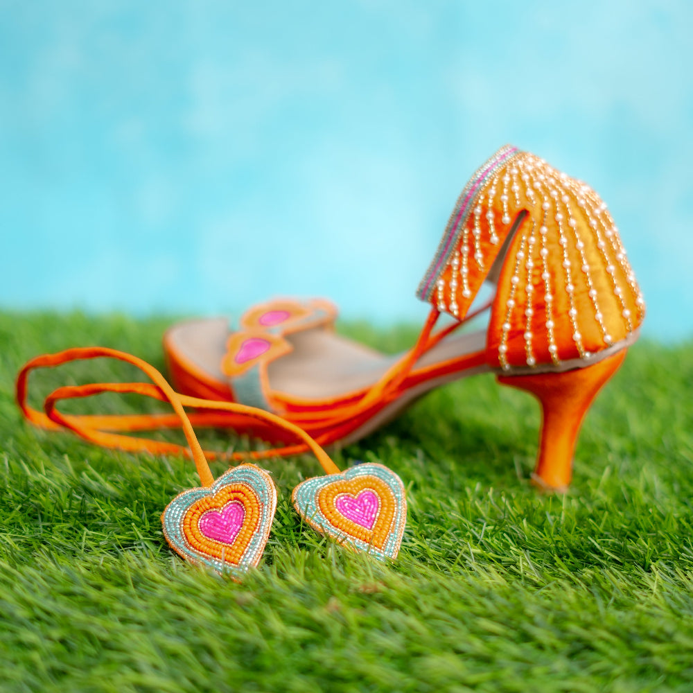 Orange high-heeled shoes with heart-shaped for haldi ceremony.