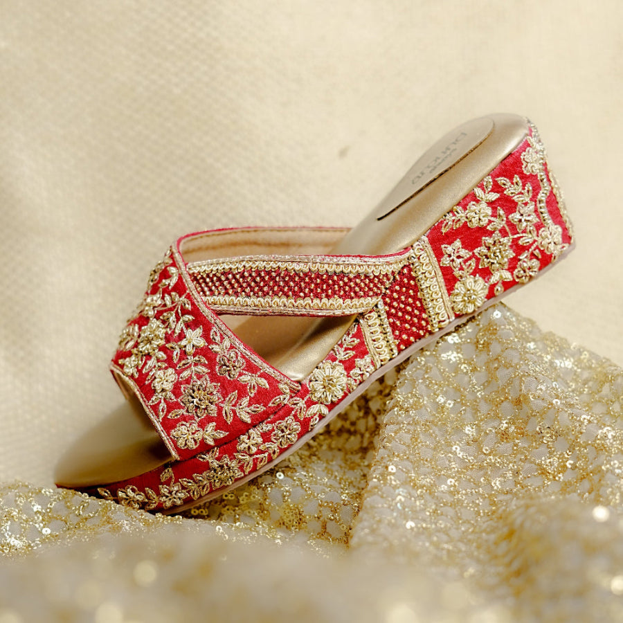 Elegant red wedge sandals with gold embellishments and cushioned support.
