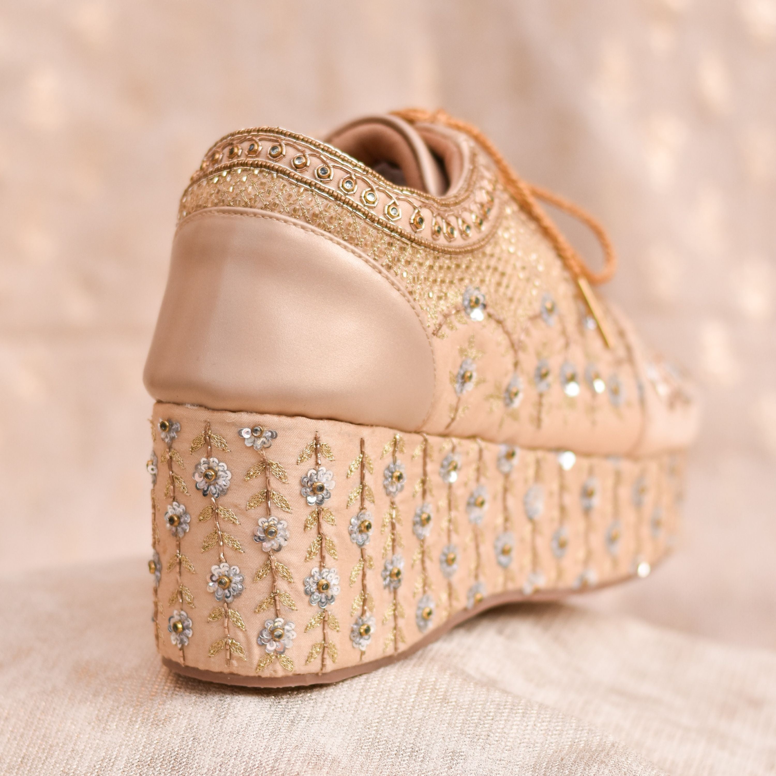 Festive lace-up sneakers with floral motifs and high wedge platform.