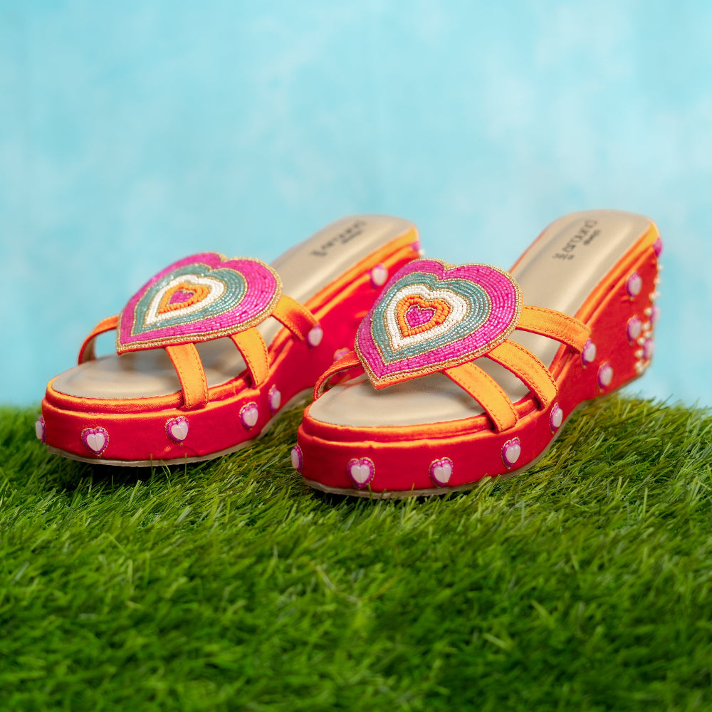 Colorful sandals with heart design on a grassy surface