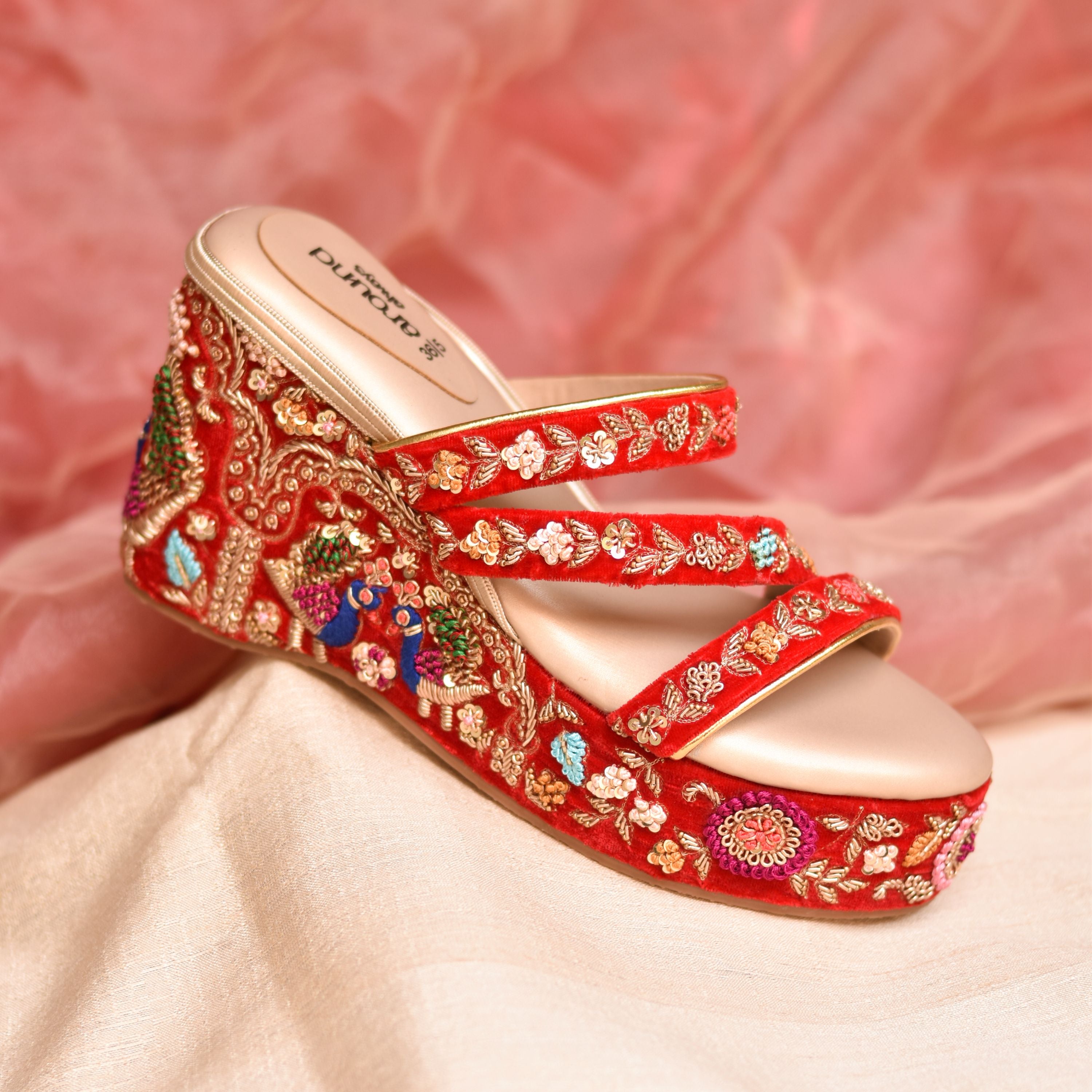Handcrafted red wedge heels with three straps and intricate threadwork.