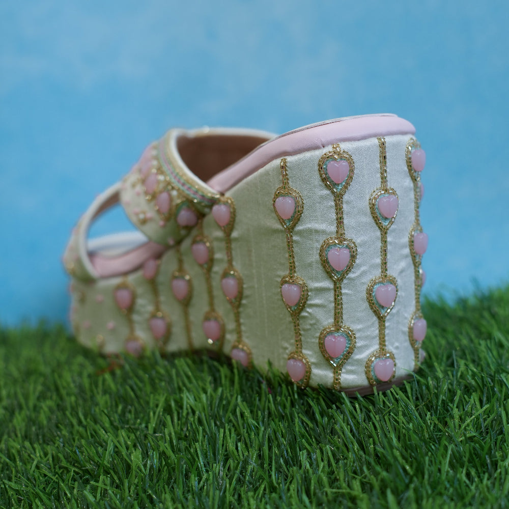Pastel pink platform sandals with gold decorative detailing
