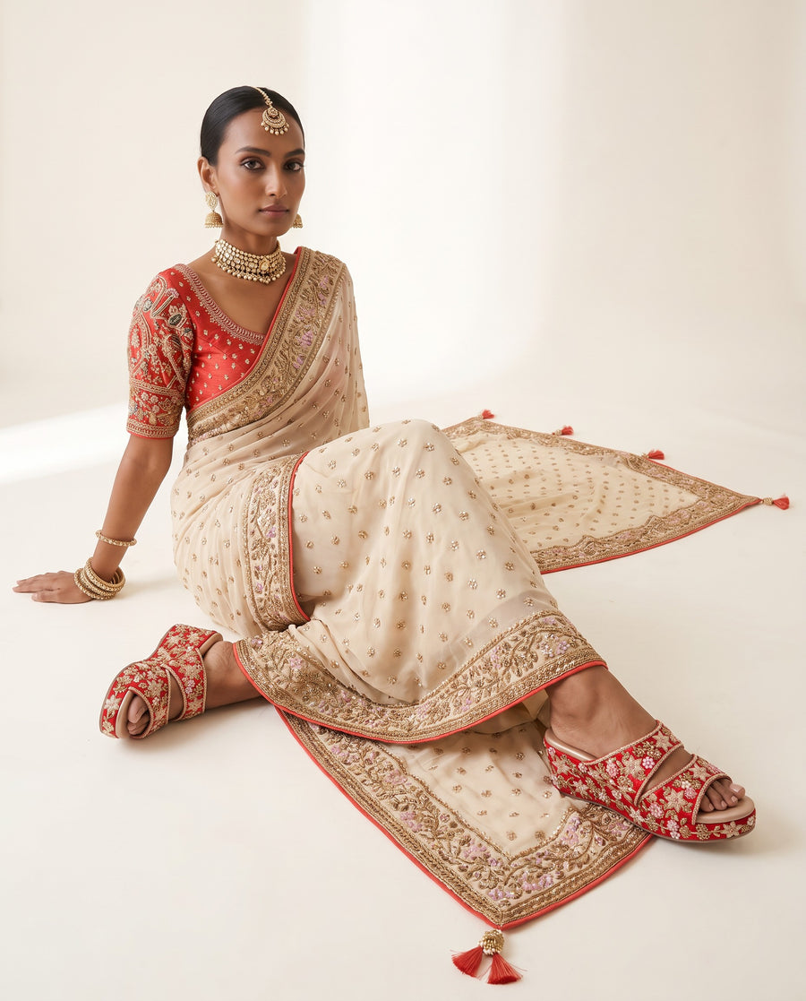 A super royal ivory Indian saree paired with a contrast red blouse and artisanal Indian heels 