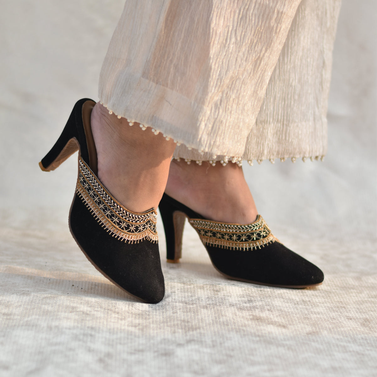 Black pencil heel mules with gold zardozi work worn with a tissue sharara pants