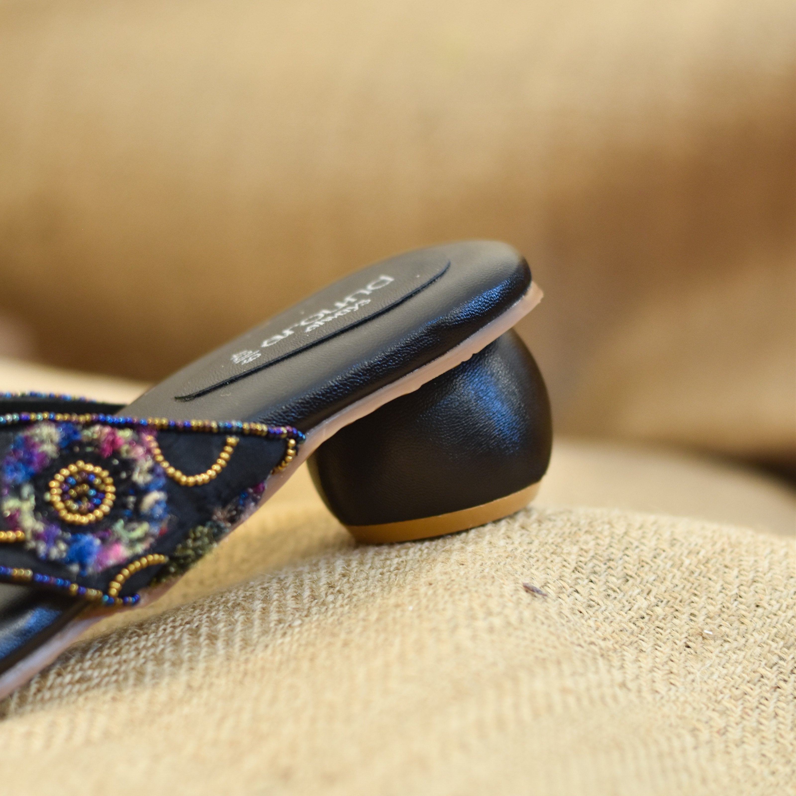 Artisan-inspired black slip-on chappals with bright yarn patterns and soft sole