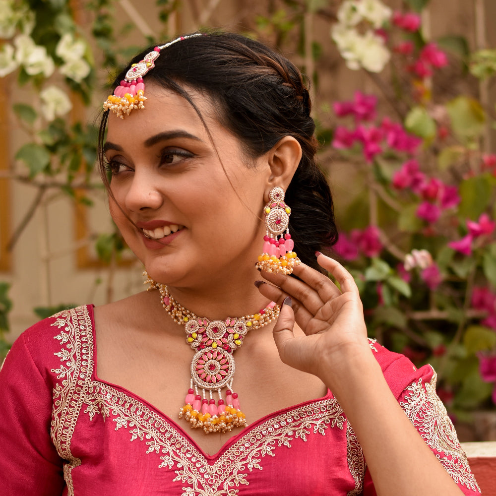 Woman in pink haldi attire with imitation jewellery made of stones and beads