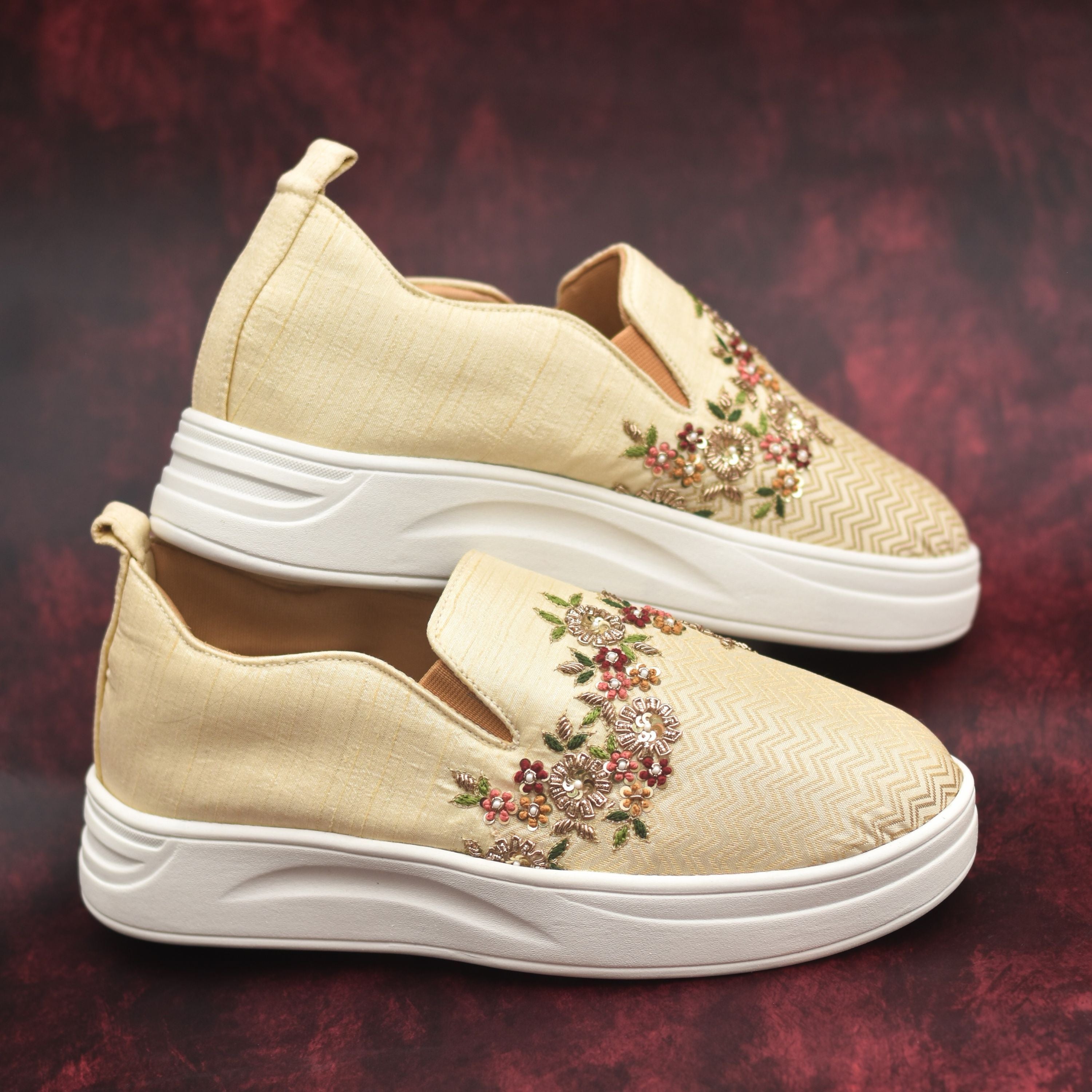 Designer ethnic sneakers featuring golden floral handwork on zig-zag fabric.