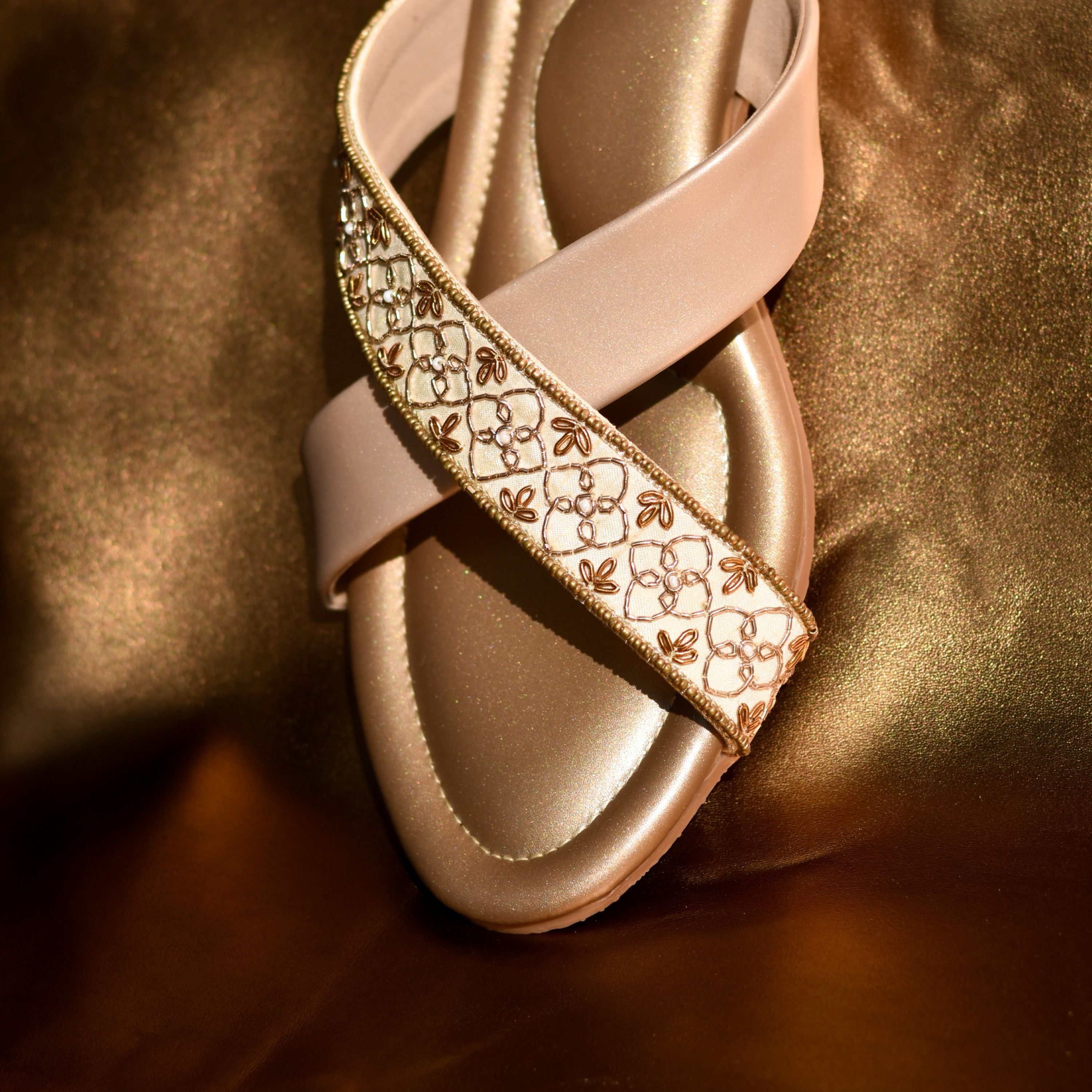 Women’s flats featuring golden base and embroidered cross straps.