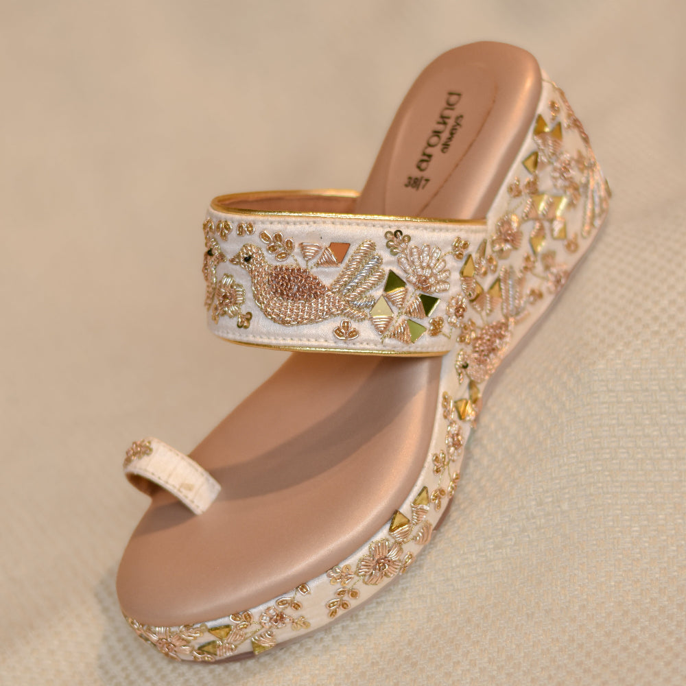 Ivory toe-ring wedge sandals with embroidered peacock motifs and mirror detailing
